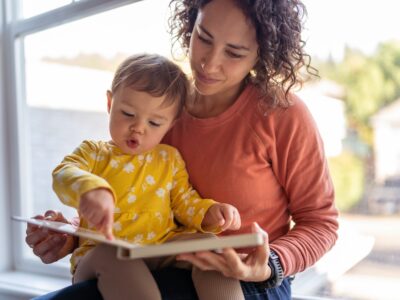 Affectionate mother reading book with adorable toddler daughter