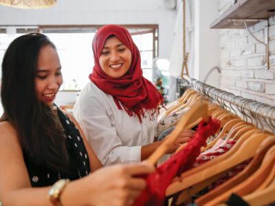 Close up two females Asian friends going shopping vintage clothes together in a thrift market