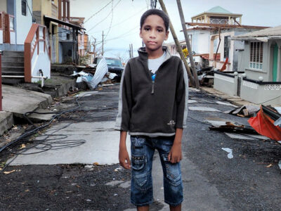 project esparanza - a young boy stands in puerto rico with the aftermath of a hurricane behind him