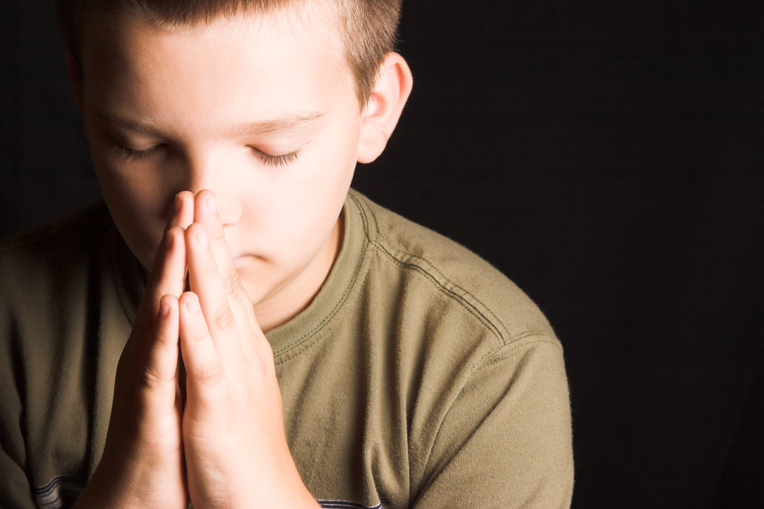 small boy praying with hands folded