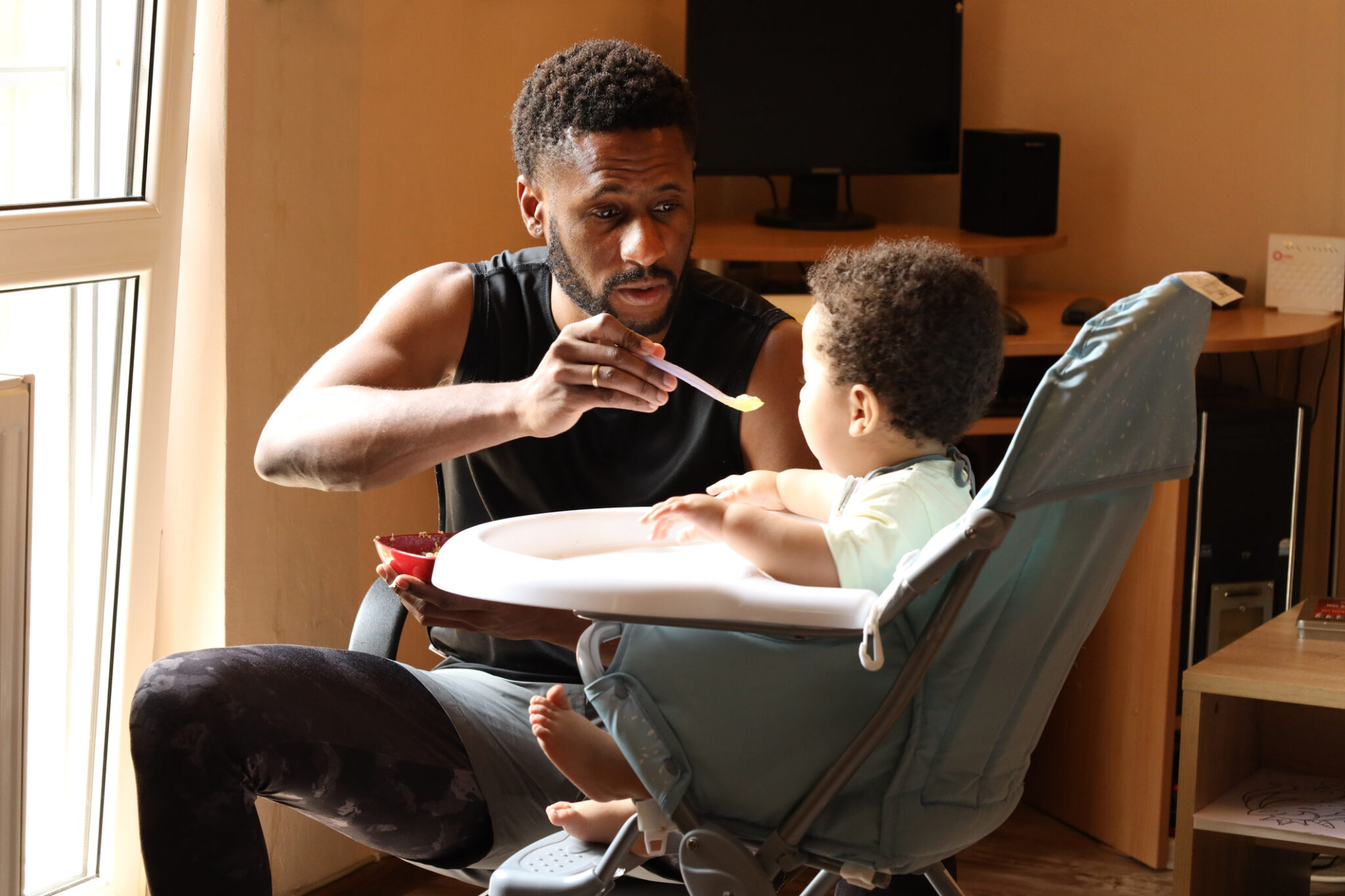 dad feeding baby in high chair